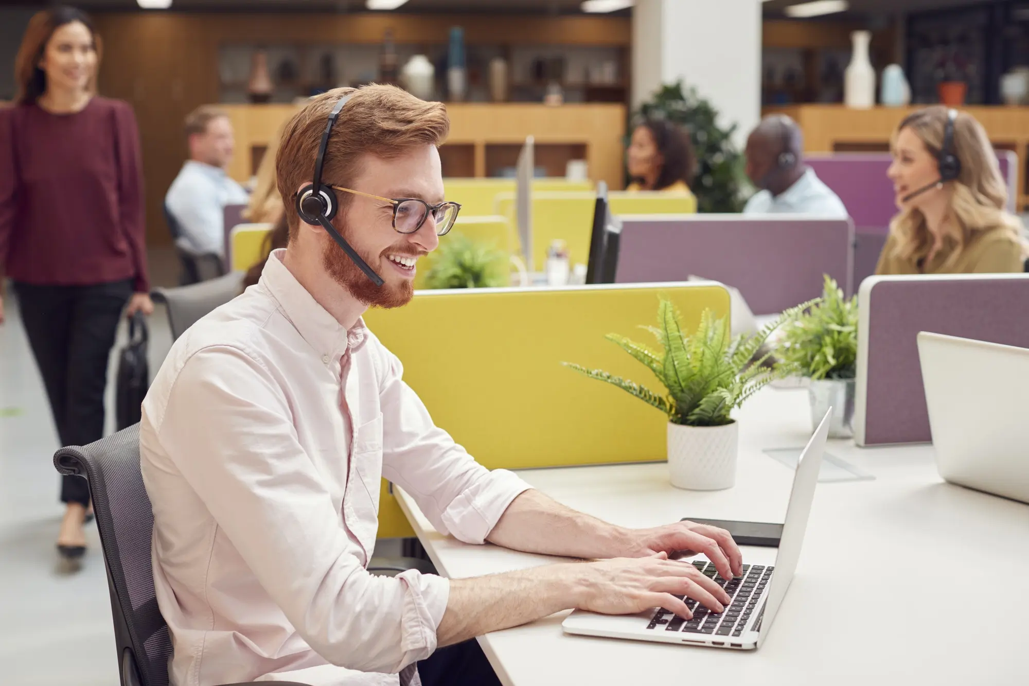 businessman-wearing-headset-talking-to-caller-in-busy-customer-services-centre