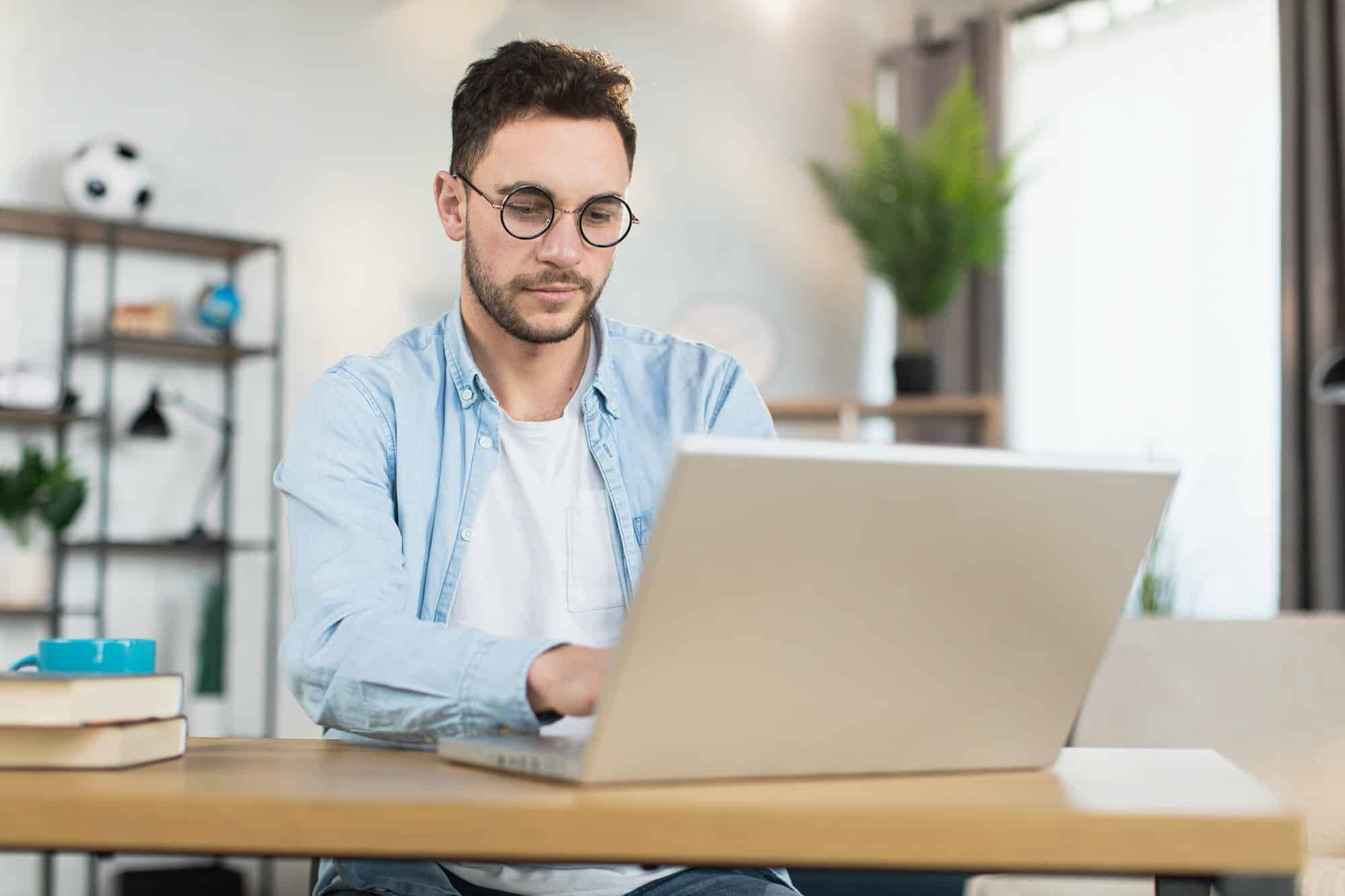 Man in eyewear sitting at desk and working on laptop