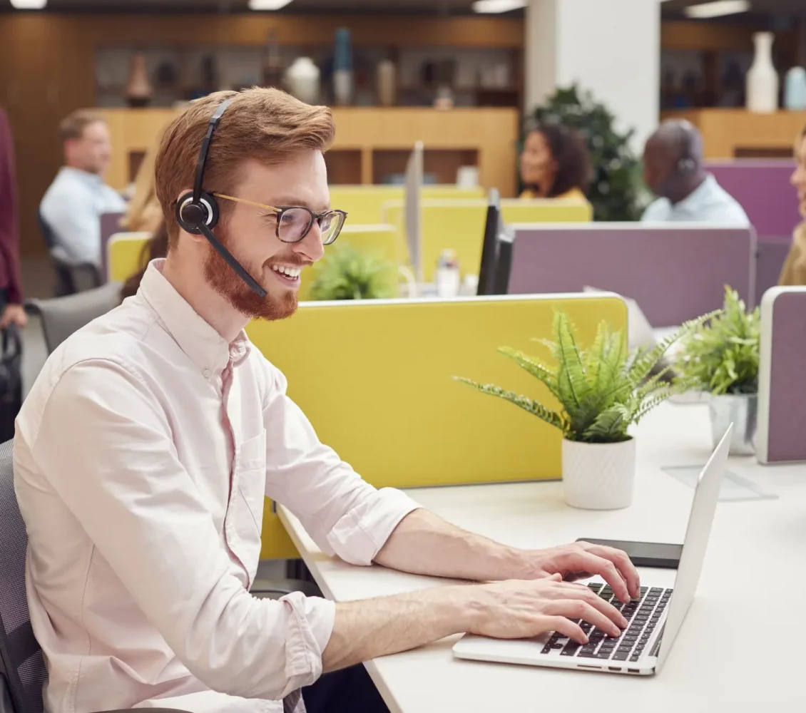 businessman-wearing-headset-talking-to-caller-in-busy-customer-services-centre