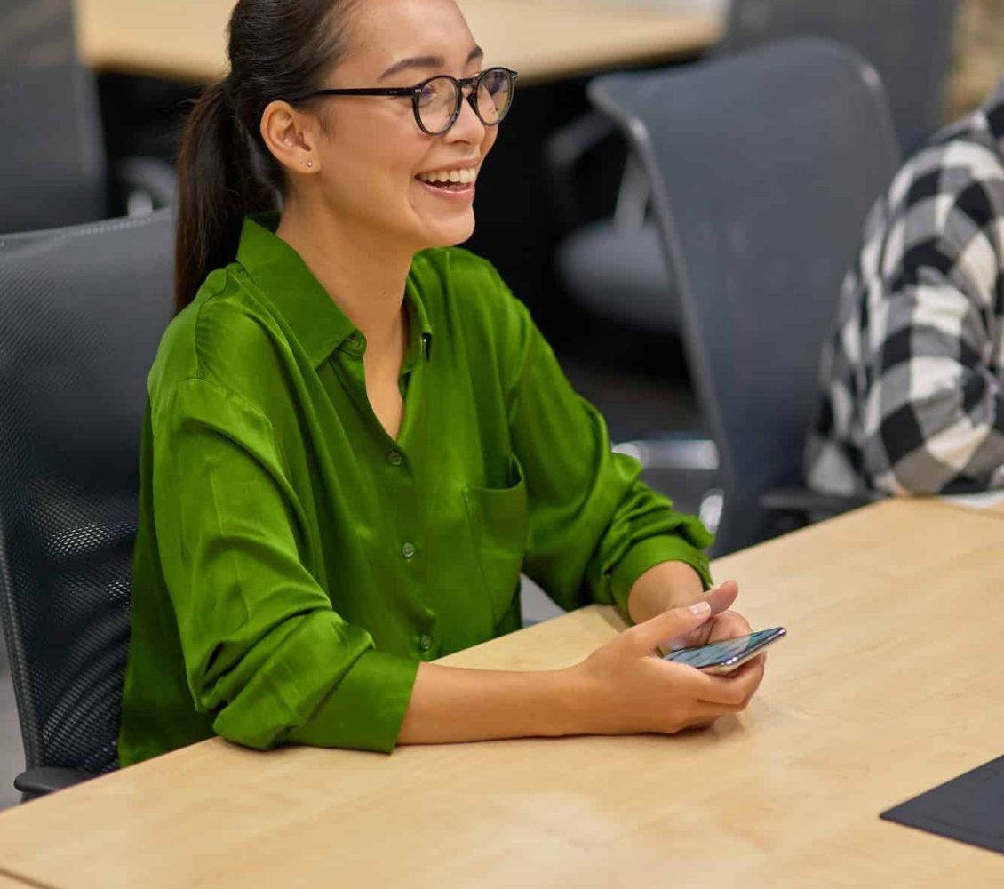 Vertical shot of a young happy asian woman, female office worker sitting at desk in the board room