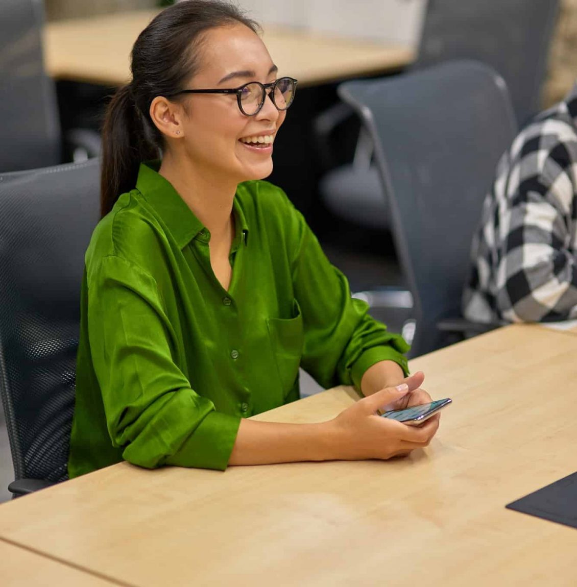 Vertical shot of a young happy asian woman, female office worker sitting at desk in the board room